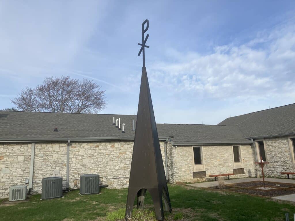St. Thomas Episcopal Church memorial garden with cross and sculpture under blue sky.