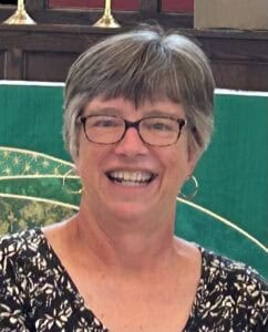 Smiling woman with short gray hair and glasses at St. Thomas Episcopal Church.